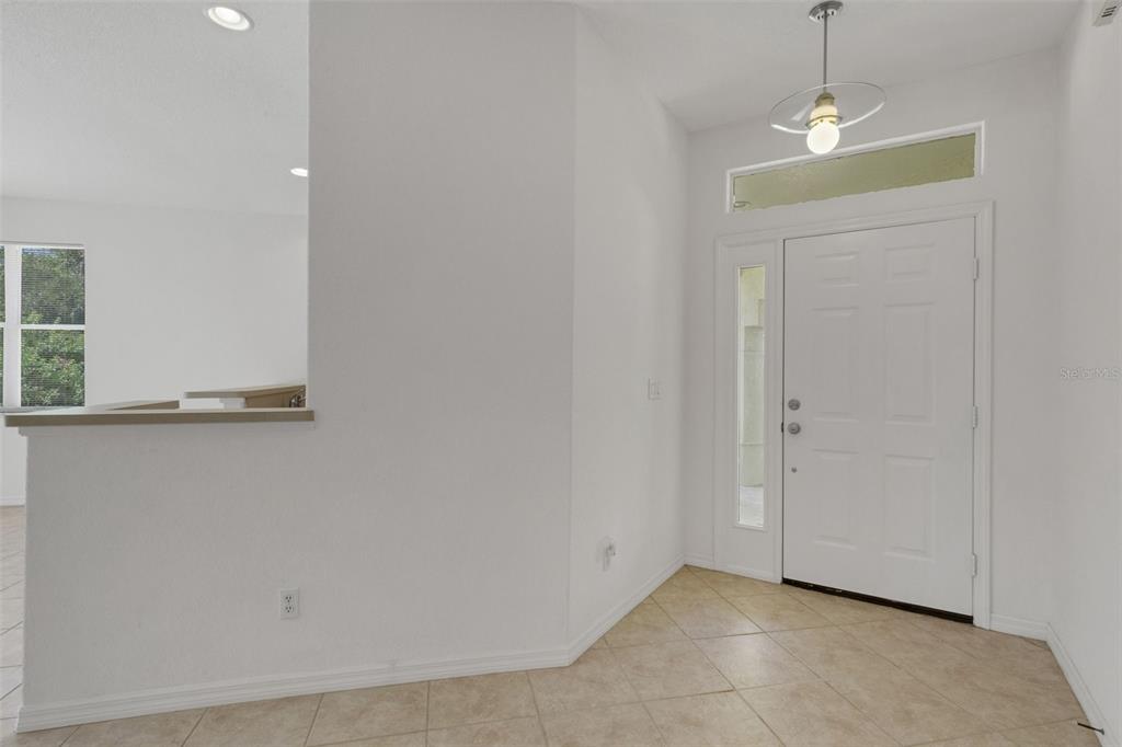 A bright entryway features a white front door, tiled flooring, and a partial wall — 26289 FEATHERSOUND DRIVE, PUNTA GORDA, FL