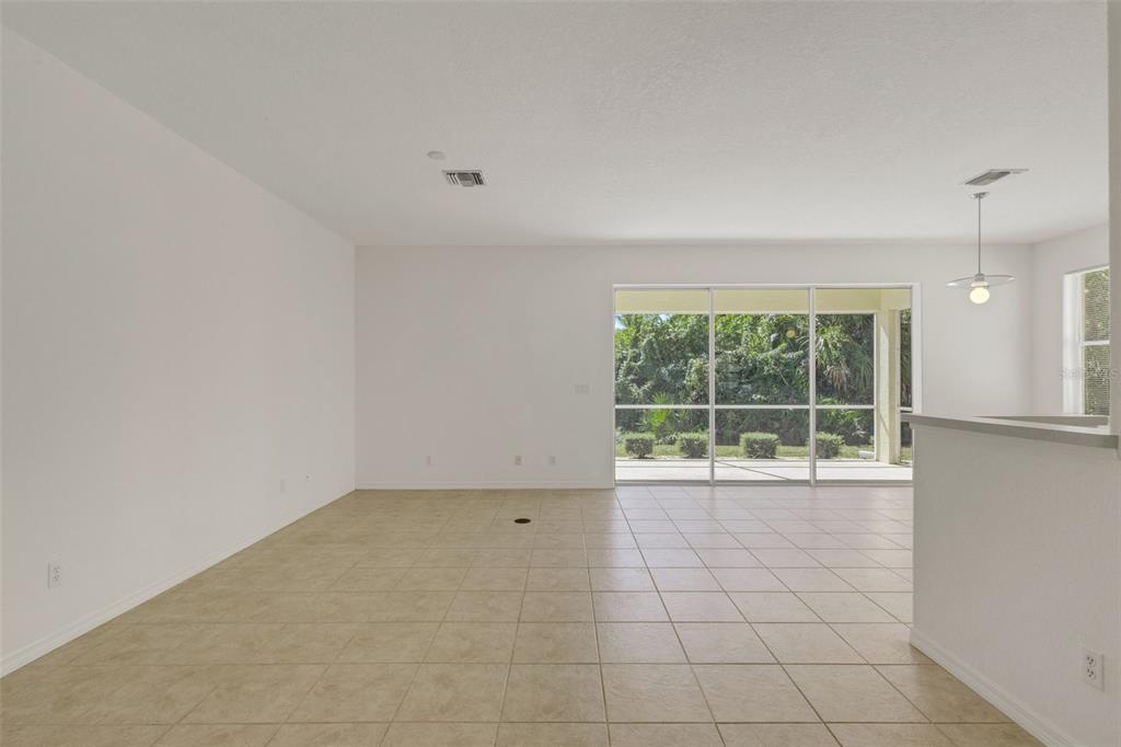 An open-concept living area with beige tile flooring and a sliding glass door to a patio — 26289 FEATHERSOUND DRIVE, PUNTA GORDA, FL