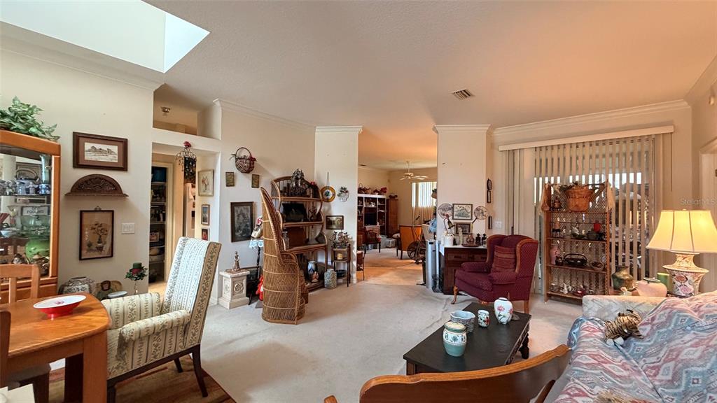 A living room with beige carpet, a red armchair, and a dining area with a skylight — 3671 E ARBOR LAKES DRIVE, HERNANDO, FL