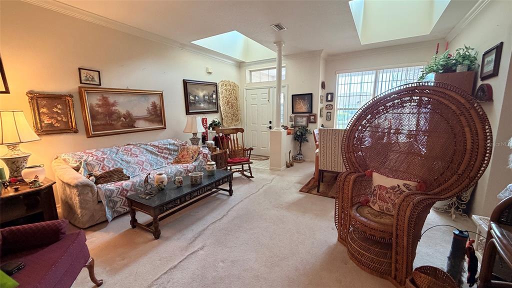 A living room features a patterned sofa, a large wicker chair, and multiple wall paintings — 3671 E ARBOR LAKES DRIVE, HERNANDO, FL
