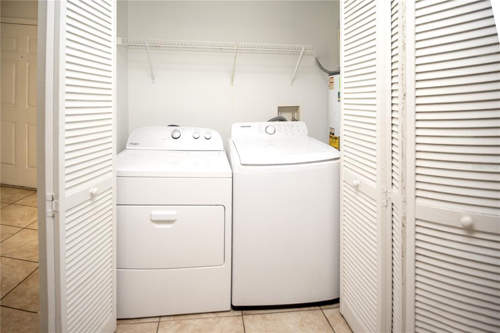 A laundry closet contains a white dryer and a white top-loading washing machine — 2814 CLUB CORTILE CIRCLE UNIT A, KISSIMMEE, FL