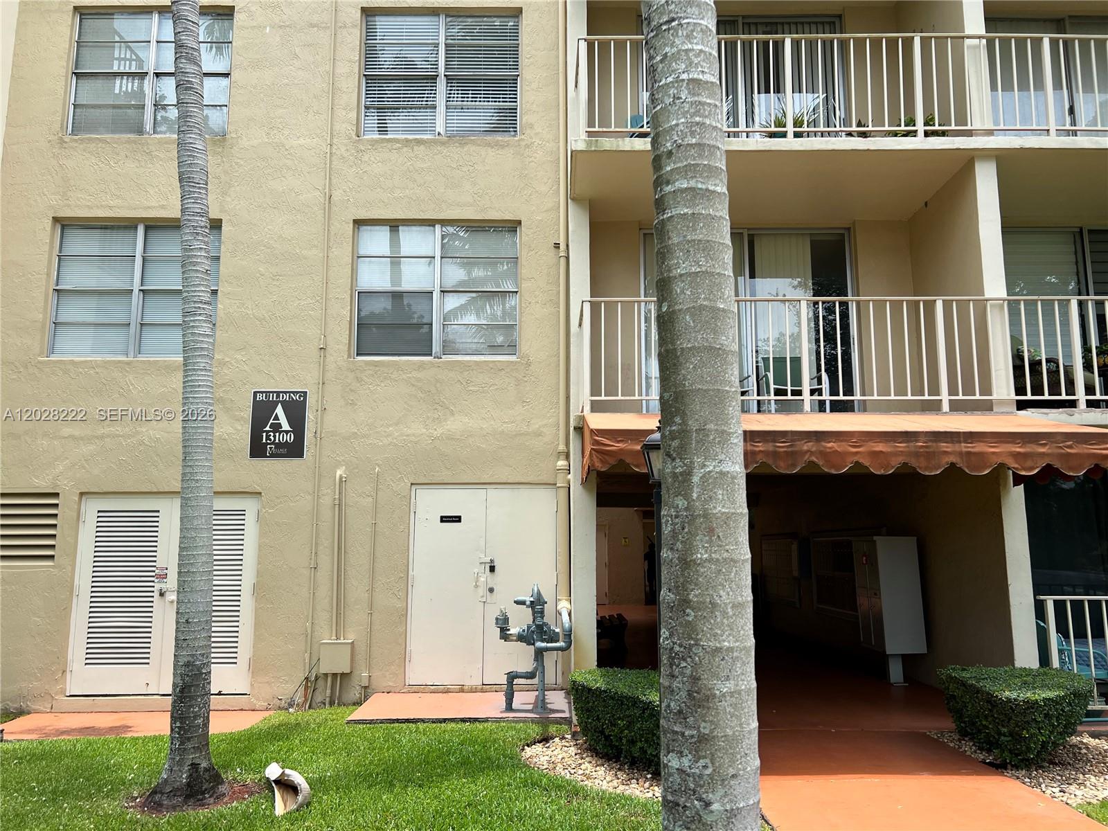 The exterior of a multi-story apartment building features a tan facade, balconies, and palm trees — 13100 SW 92nd Ave # 212, Miami FL 33176, MIAMI, FL