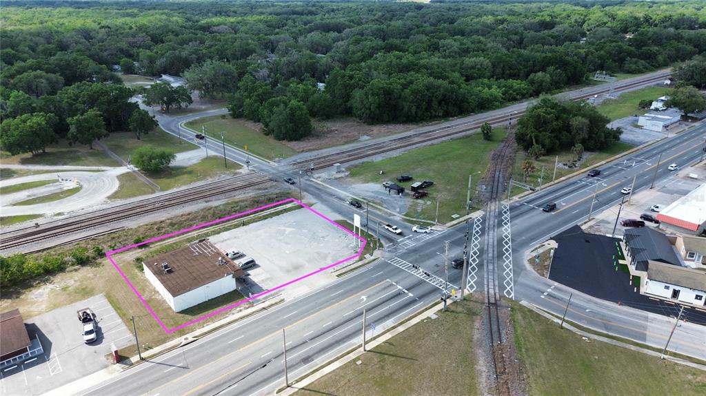 An aerial view shows a commercial building with a parking lot near a railroad crossing — 405 S MAIN STREET, WILDWOOD, FL