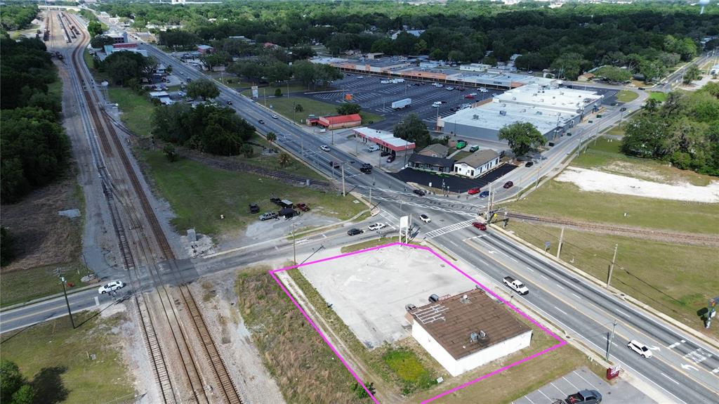 An aerial view shows a vacant commercial lot with a small building near railroad tracks — 405 S MAIN STREET, WILDWOOD, FL