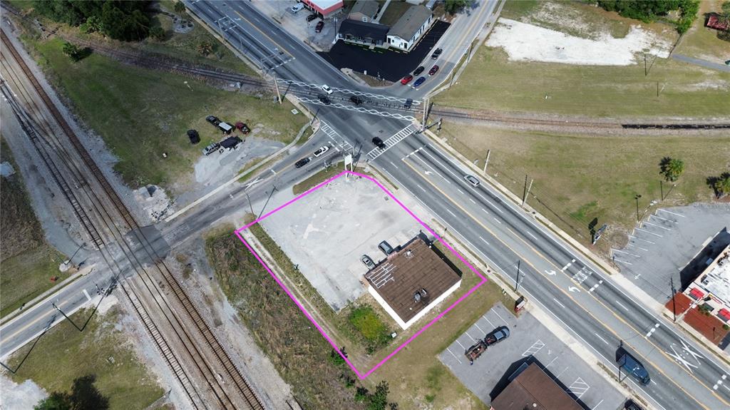 An aerial view shows a commercial property outlined in pink near a road and railroad — 405 S MAIN STREET, WILDWOOD, FL