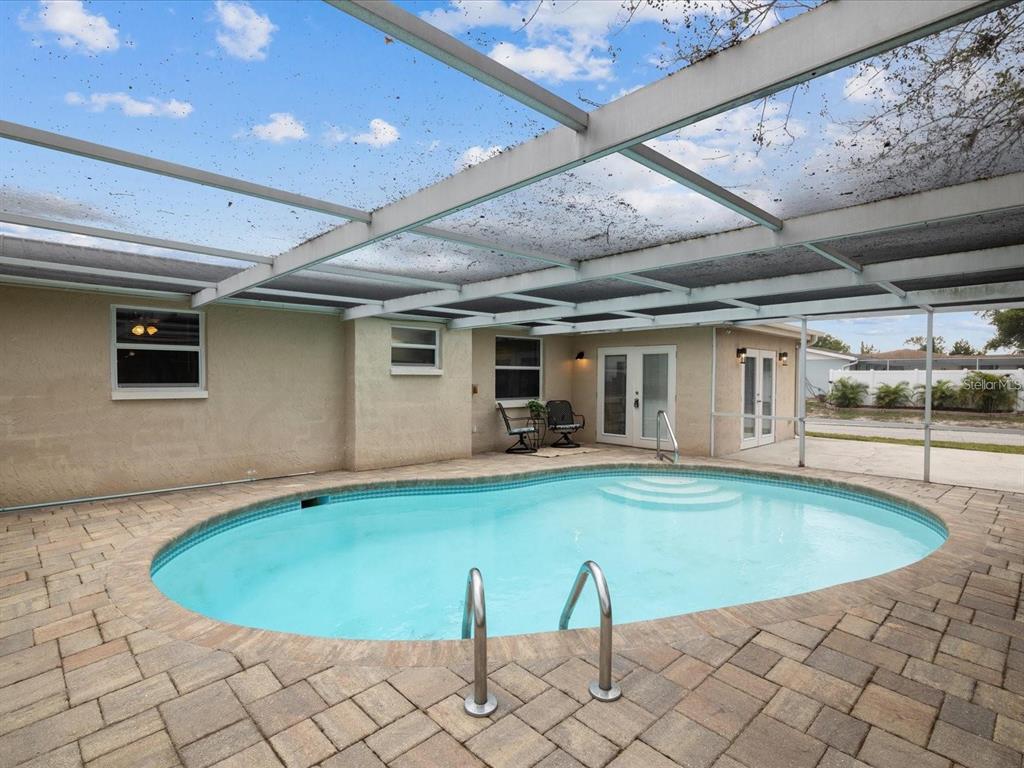 An outdoor swimming pool with a screen enclosure and a paver patio — 9331 RAINBOW LANE, PORT RICHEY, FL