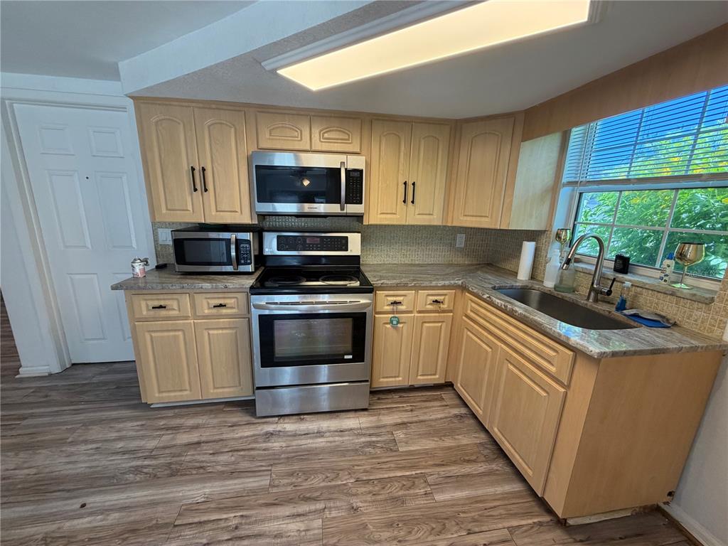 A kitchen features light wood cabinets, stainless steel appliances, and granite countertops — 9331 RAINBOW LANE, PORT RICHEY, FL