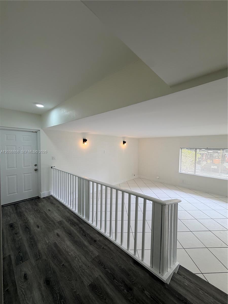 An interior view shows a split-level room with white tile flooring, wood-look laminate, and railings — 4705 SW 62nd Ave # 104, Davie FL 33314, DAVIE, FL