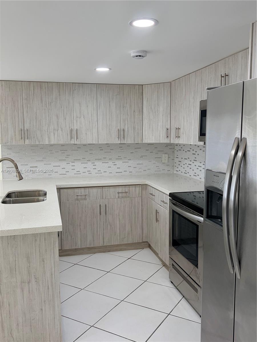 A kitchen features light wood-grain cabinets, stainless steel appliances, and a white tiled floor — 4705 SW 62nd Ave # 104, Davie FL 33314, DAVIE, FL