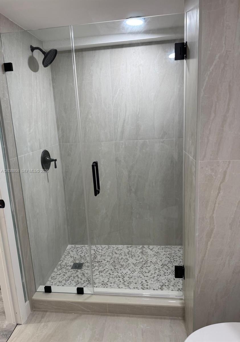 A walk-in shower features gray stone-look wall tiles, a pebble floor, and black hardware — 4705 SW 62nd Ave # 104, Davie FL 33314, DAVIE, FL
