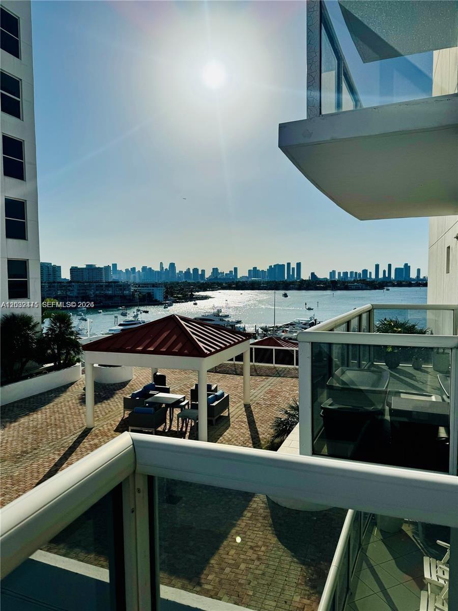 A balcony view overlooks a patio with a gazebo, a marina, and a distant city skyline — 1900 Sunset Harbour Dr # 815, Miami Beach FL 33139, MIAMI BEACH, FL