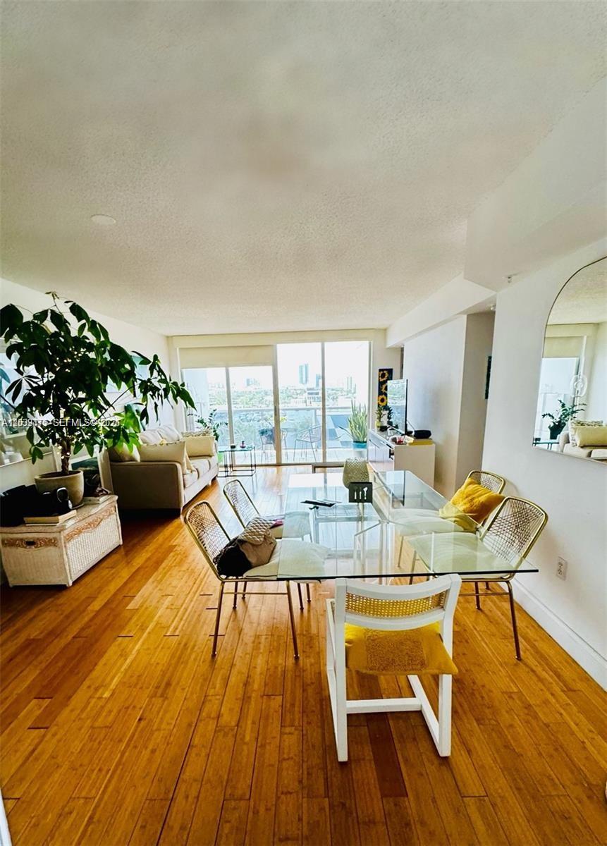A dining area with a glass table and chairs sits before a living room balcony — 1900 Sunset Harbour Dr # 815, Miami Beach FL 33139, MIAMI BEACH, FL