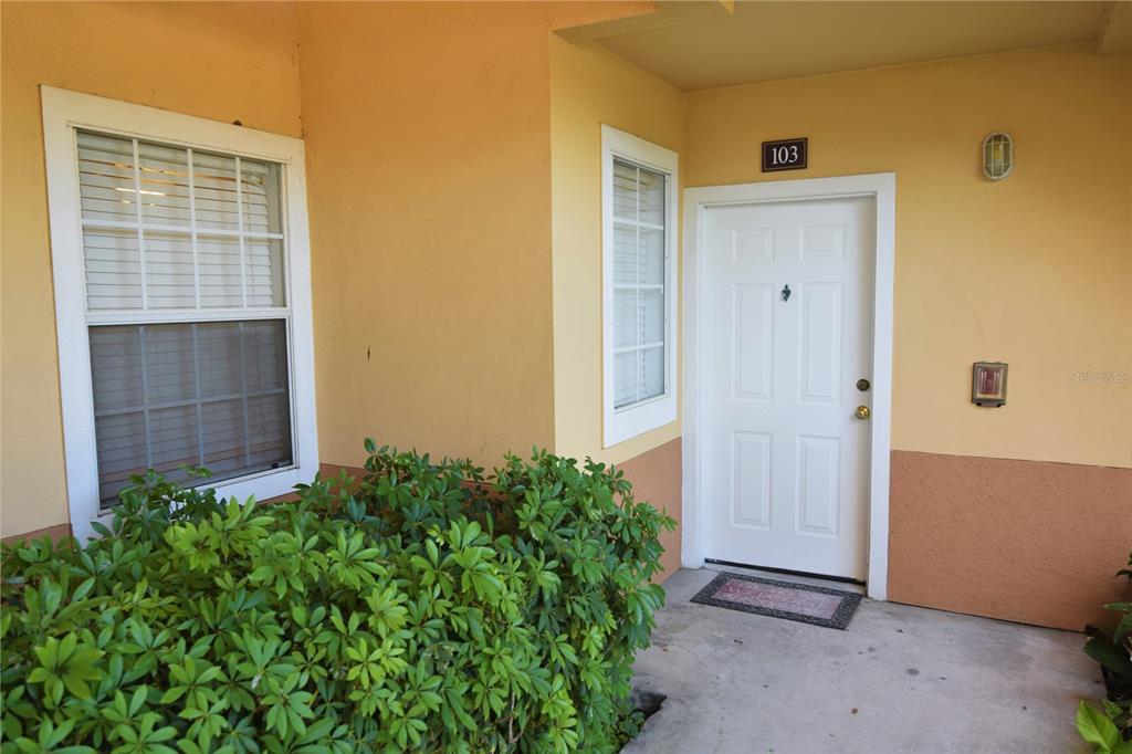 The exterior entrance of a residential unit features a white door labeled 103 — 1185 VILLAGIO CIRCLE UNIT 103, SARASOTA, FL