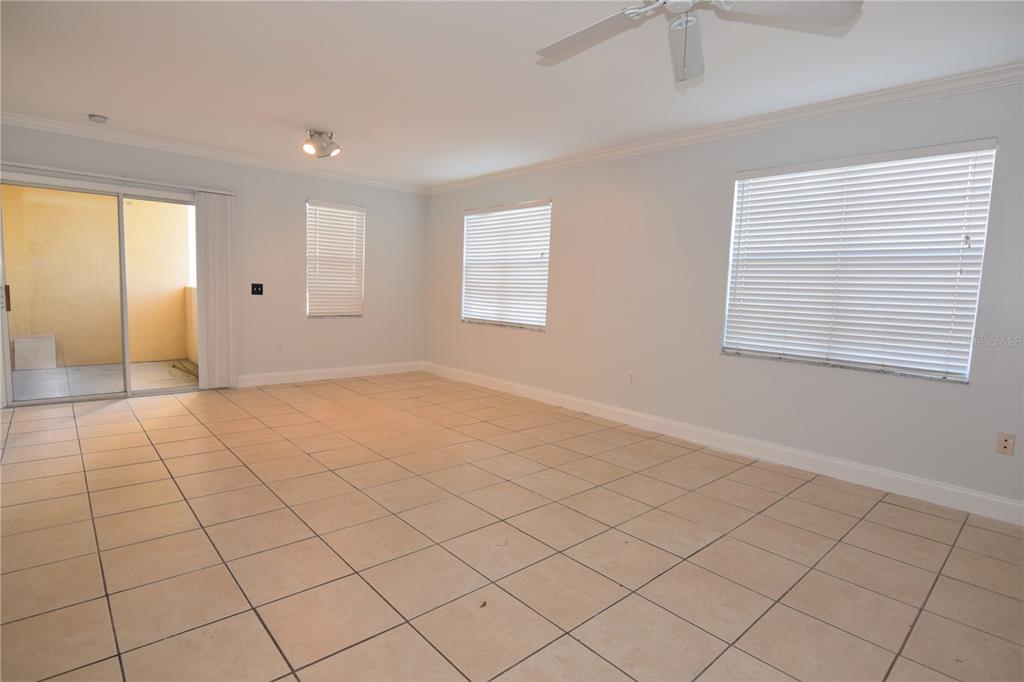 An empty room with light-colored tile flooring, white walls, windows with blinds, and a ceiling fan — 1185 VILLAGIO CIRCLE UNIT 103, SARASOTA, FL