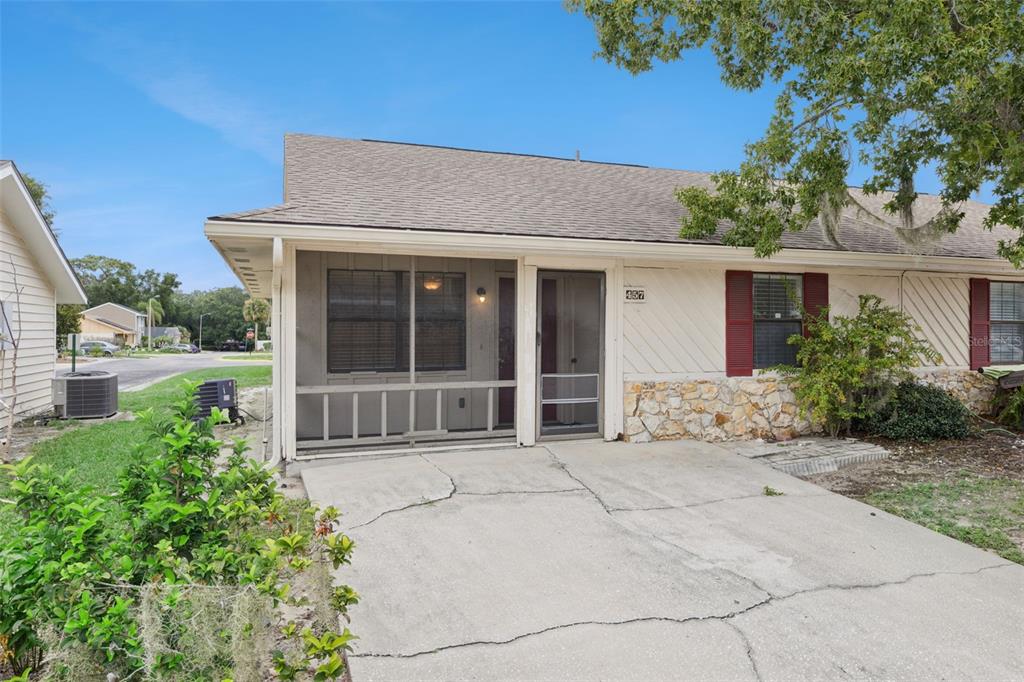 A single-story residential building features a screened-in front porch, a cracked concrete driveway, and stone siding — 457 HEMLOCK STREET, ALTAMONTE SPRINGS, FL