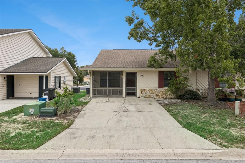 A single-story house with a screened porch, stone accents, and a cracked concrete driveway — 457 HEMLOCK STREET, ALTAMONTE SPRINGS, FL
