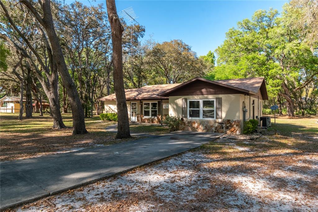 A single-story house with a stone facade and a concrete driveway surrounded by trees — 3005 SE 160TH LANE ROAD, SUMMERFIELD, FL