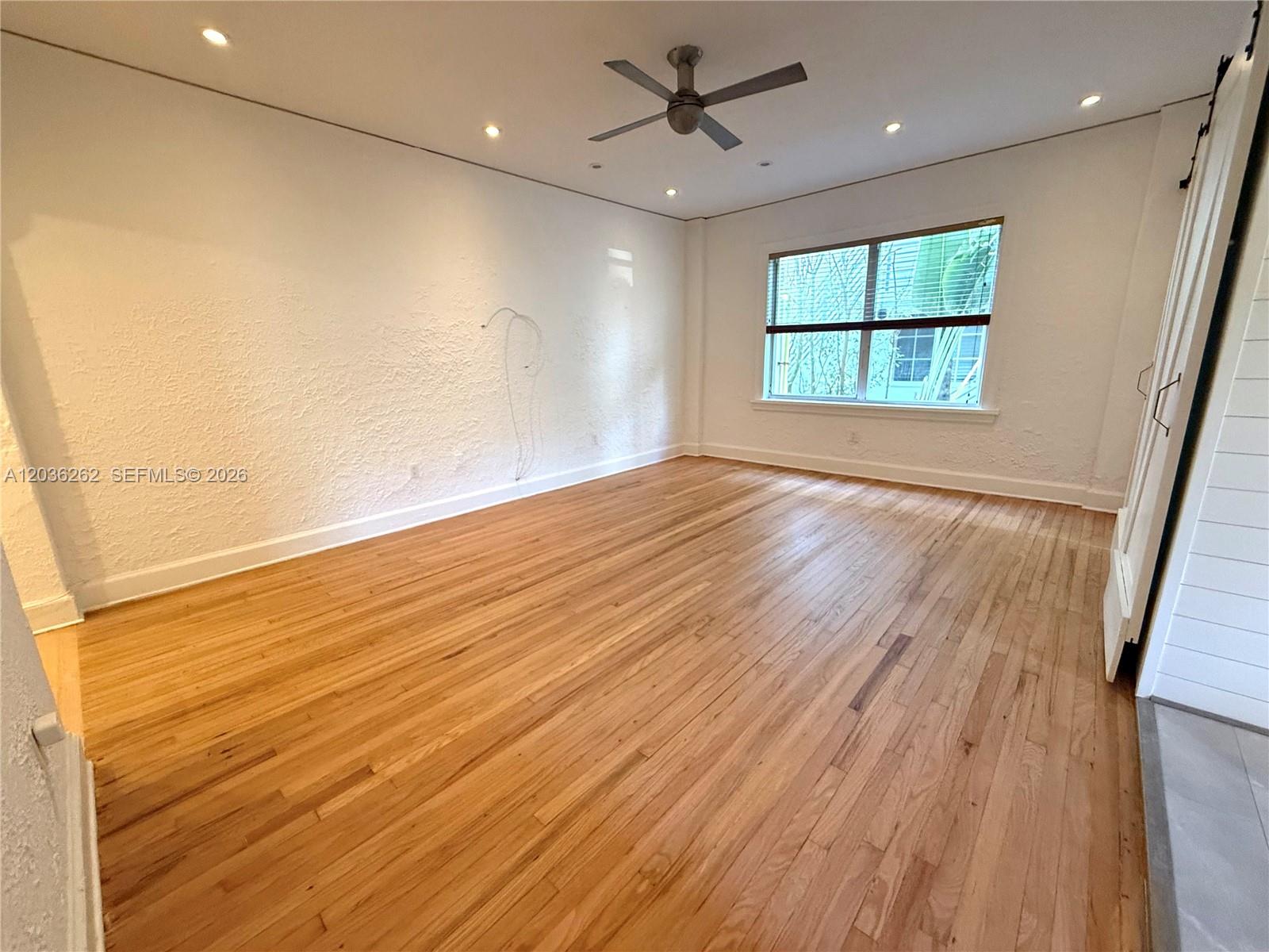 An empty room features hardwood floors, a ceiling fan, and textured white walls — 900 16th St # 108, Miami Beach FL 33139, MIAMI BEACH, FL