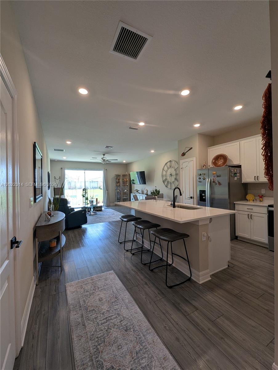 A kitchen with a white island and bar stools overlooks an open-concept living area — 5103 Joyous Pl, Fort Pierce FL 34947, FORT PIERCE, FL