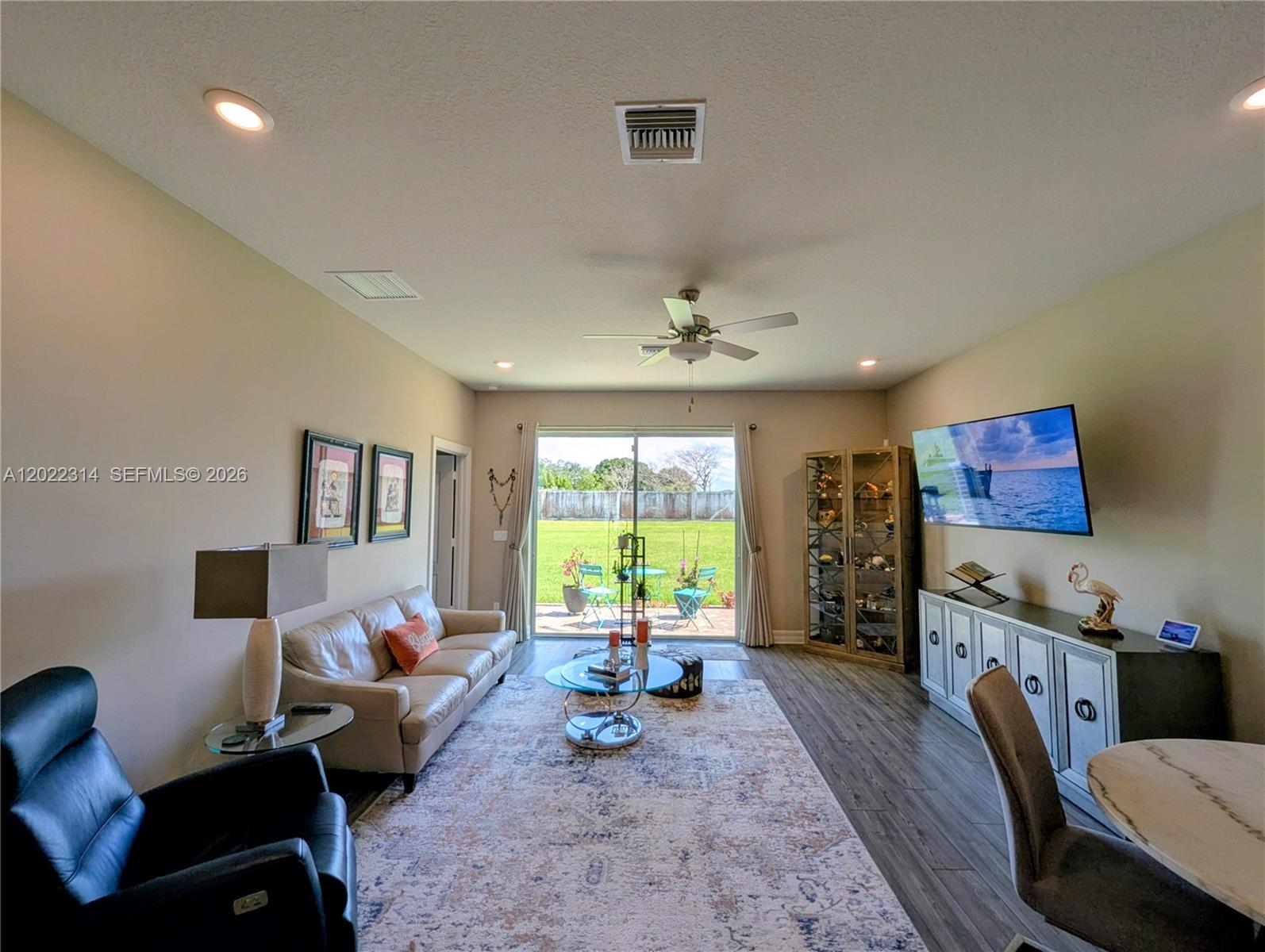 A living room features a beige sofa, a black recliner, and a wall-mounted television — 5103 Joyous Pl, Fort Pierce FL 34947, FORT PIERCE, FL