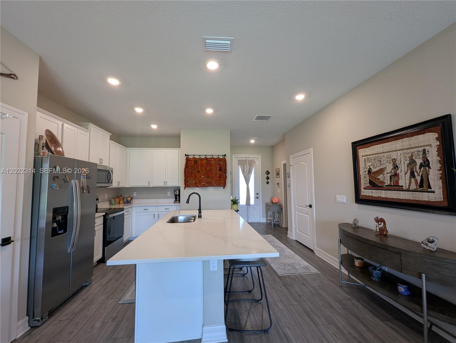 A kitchen features white cabinets, a large central island with a sink, and wood-look flooring — 5103 Joyous Pl, Fort Pierce FL 34947, FORT PIERCE, FL