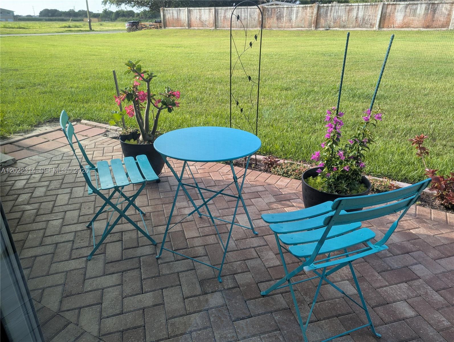 A turquoise bistro set sits on a brick patio in a grassy backyard — 5103 Joyous Pl, Fort Pierce FL 34947, FORT PIERCE, FL