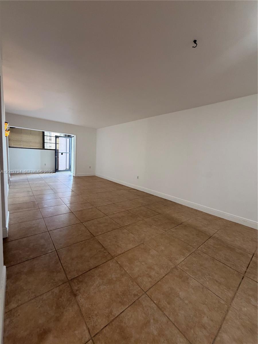 An empty room features beige tile flooring, white walls, and a glass door leading outside — 1300 SW 122nd Ave # 2, Miami FL 33184, MIAMI, FL