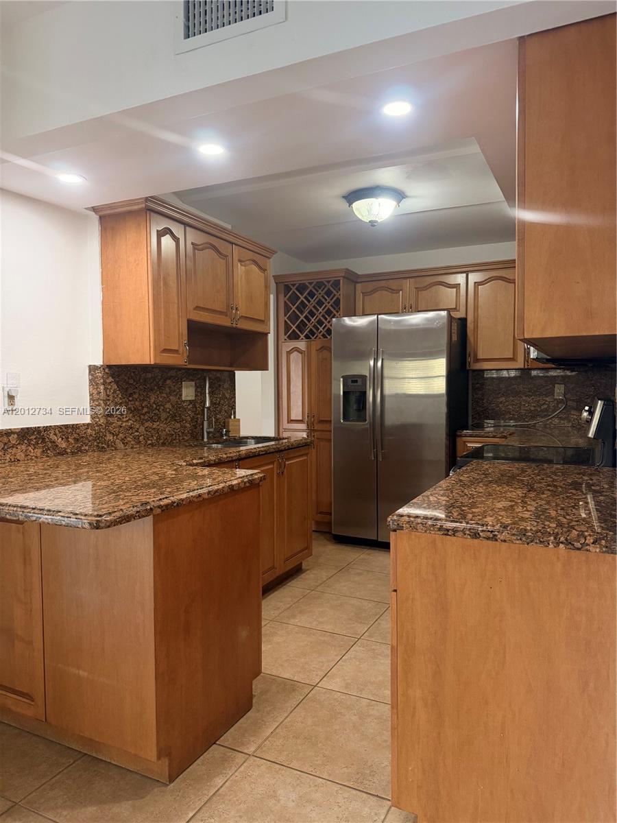 A kitchen features wood cabinets, granite countertops, stainless steel appliances, and tile flooring — 1300 SW 122nd Ave # 2, Miami FL 33184, MIAMI, FL