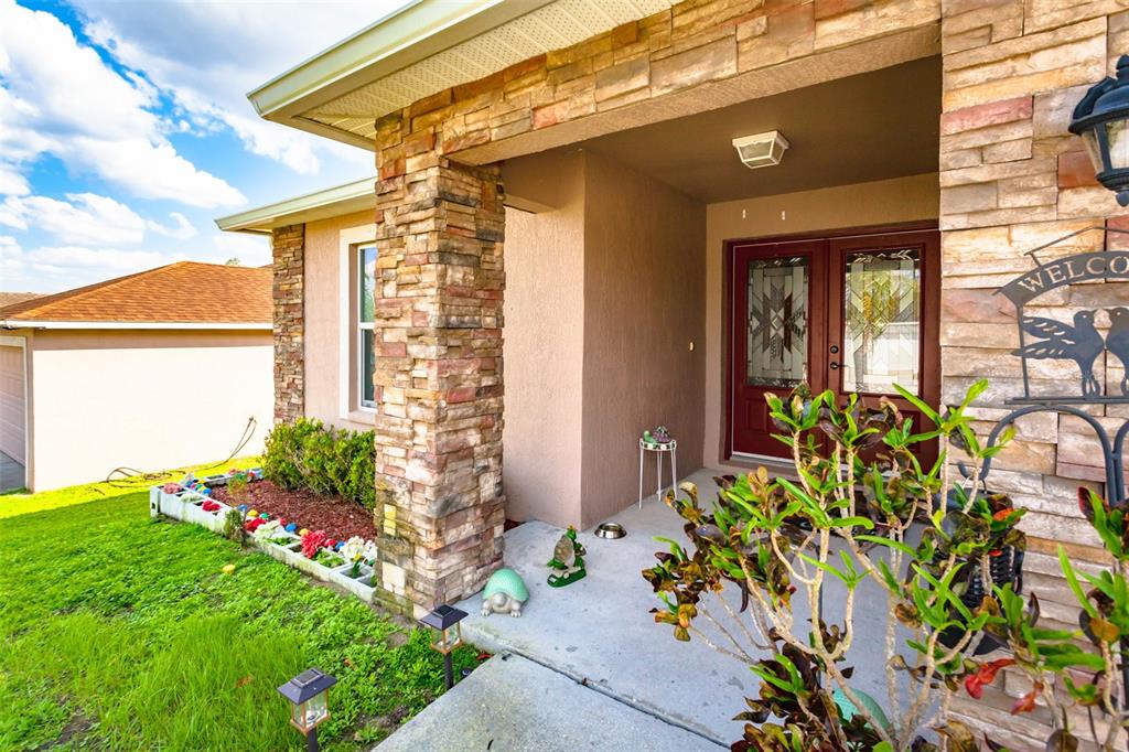 The exterior view shows a house entrance with stone pillars, a red door, and landscaping — 215 CAPTAIN HOOK WAY, DAVENPORT, FL