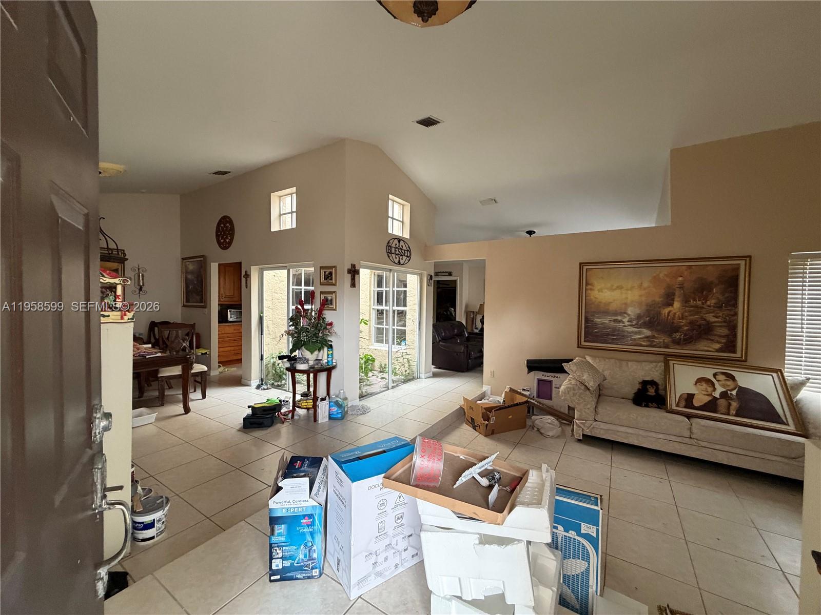 A living room with tile floors, vaulted ceilings, and sliding glass doors leading to a patio — 14249 SW 103rd Ter, Miami FL 33186, MIAMI, FL