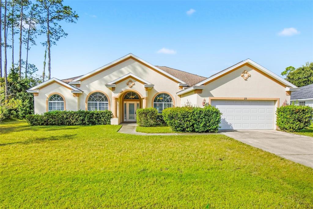 A single-story house with a beige stucco exterior, arched windows, and a two-car garage — 29 EAST DIAMOND DRIVE, PALM COAST, FL