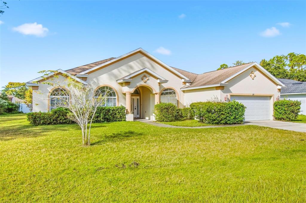 A single-story house with a beige stucco exterior, arched windows, and a two-car garage — 29 EAST DIAMOND DRIVE, PALM COAST, FL