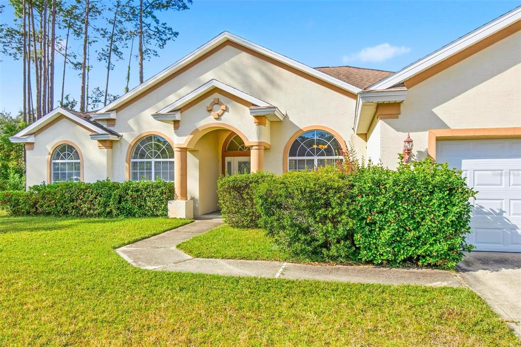 A single-story house with a beige stucco exterior, arched windows, and a front-facing garage — 29 EAST DIAMOND DRIVE, PALM COAST, FL