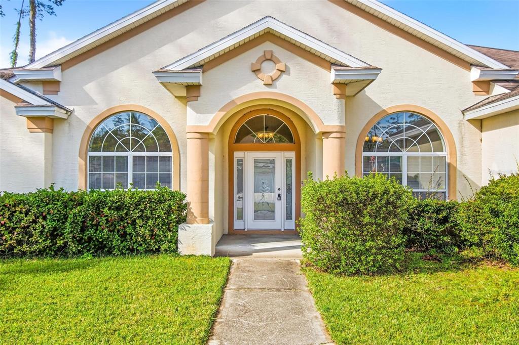 The front exterior of a house features a concrete walkway leading to a glass-paneled door — 29 EAST DIAMOND DRIVE, PALM COAST, FL
