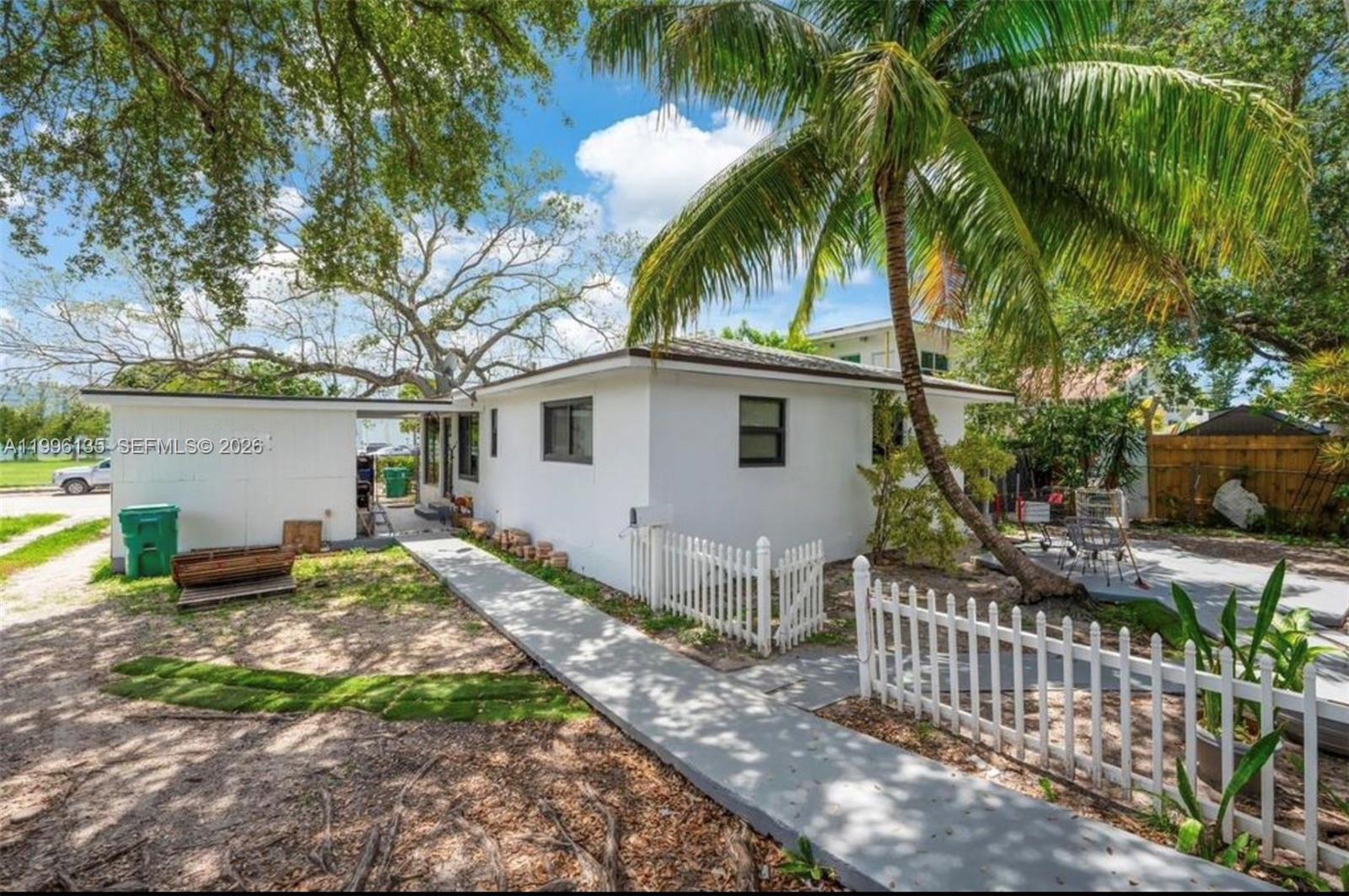 A white single-story house with a palm tree, a white picket fence, and a concrete walkway — 7625 NW 4th Ct, Miami FL 33150, MIAMI, FL