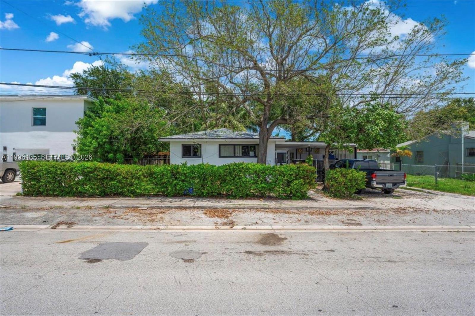 A single-story white house is partially obscured by a large tree and a green hedge — 7625 NW 4th Ct, Miami FL 33150, MIAMI, FL