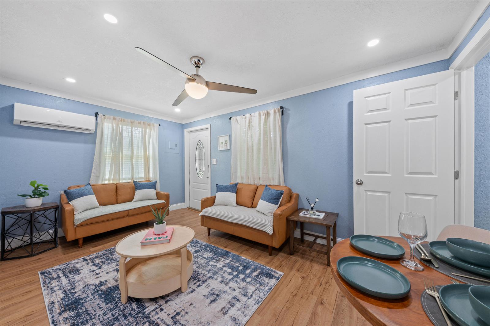 A living room with blue walls, two tan sofas, a coffee table, and wood flooring — 420 Avenida Alegre # 3, West Palm Beach FL 33405, WEST PALM BEACH, FL