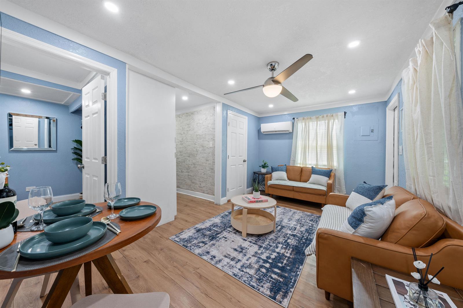 A living room and dining area feature light blue walls, wood flooring, and leather sofas — 420 Avenida Alegre # 3, West Palm Beach FL 33405, WEST PALM BEACH, FL