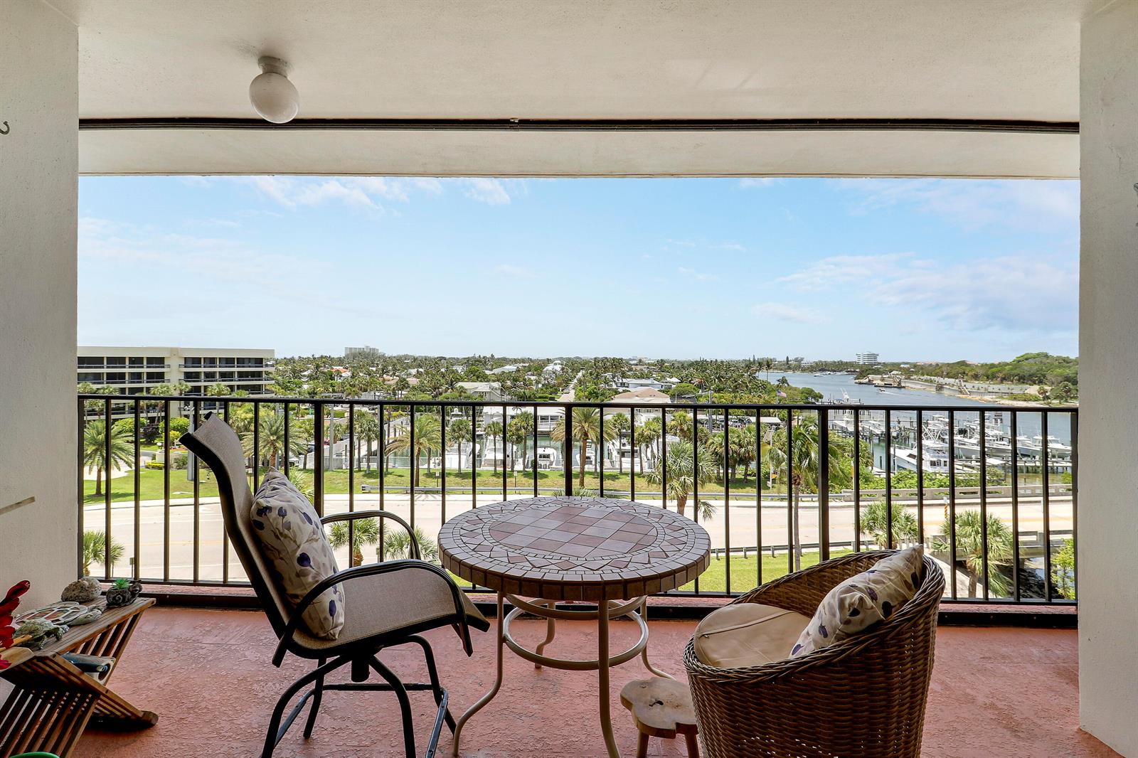 A balcony with a table and two chairs overlooks a waterway, boats, and residential buildings — 225 S Beach Road # 605, Jupiter FL 33469, JUPITER, FL