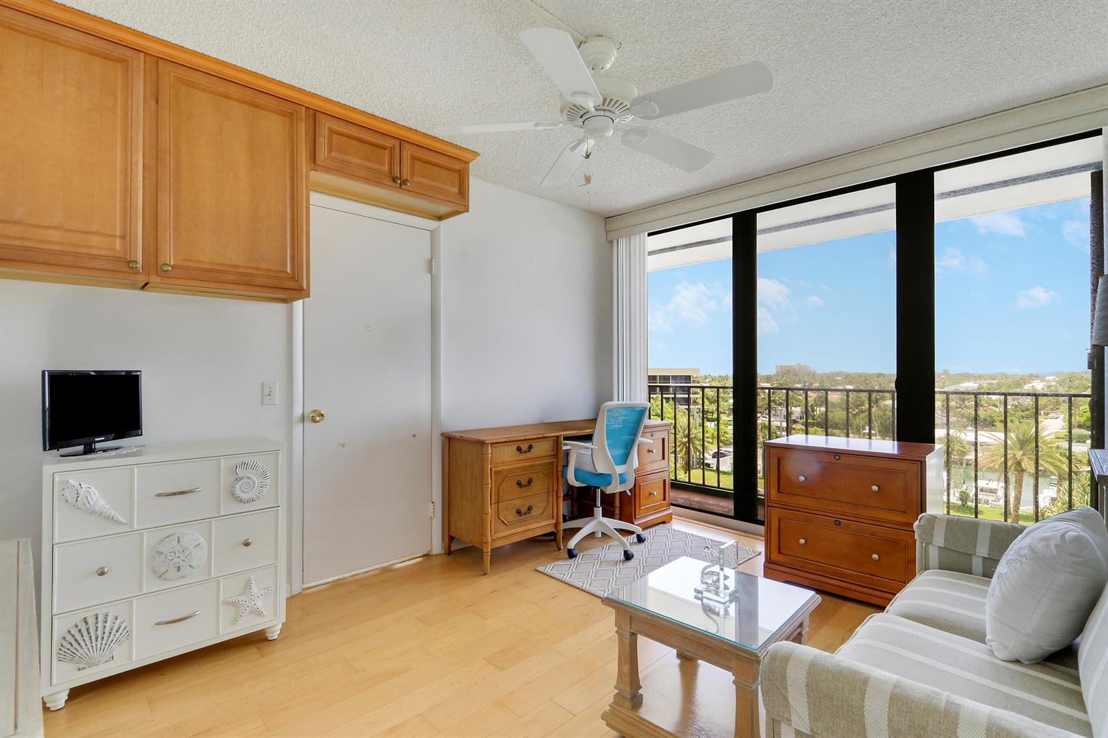 A home office with a desk, white dresser, sofa, and a balcony overlooking a waterway — 225 S Beach Road # 605, Jupiter FL 33469, JUPITER, FL