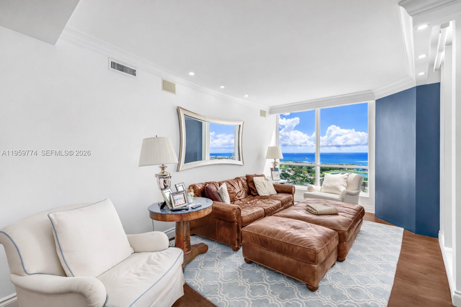 A living room features brown leather furniture, a light blue patterned rug, and floor-to-ceiling windows — 1900 Sunset Harbour Dr, Miami Beach FL 33139, MIAMI BEACH, FL