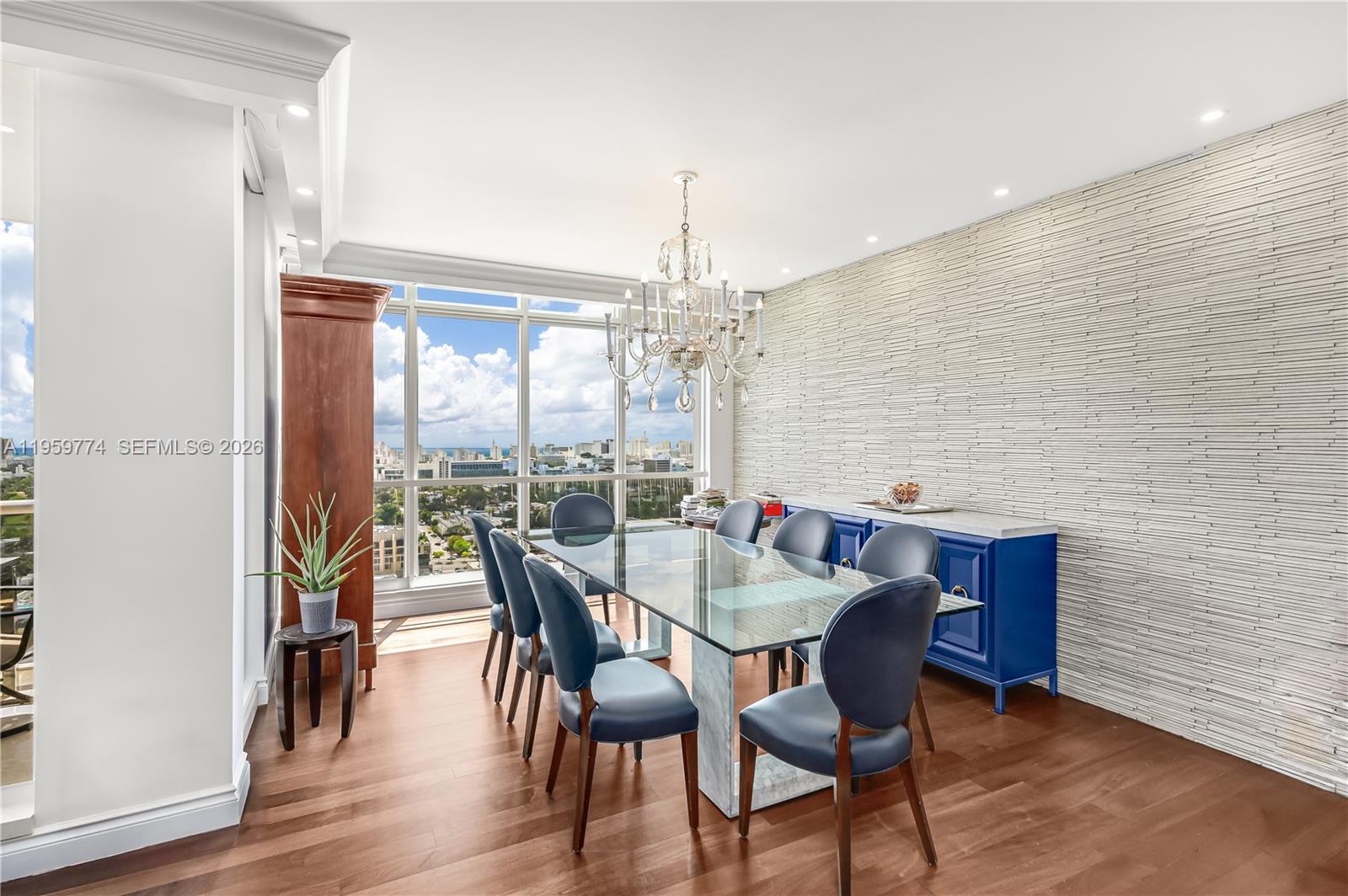 A dining room features a glass table, blue chairs, a chandelier, and a textured wall — 1900 Sunset Harbour Dr, Miami Beach FL 33139, MIAMI BEACH, FL