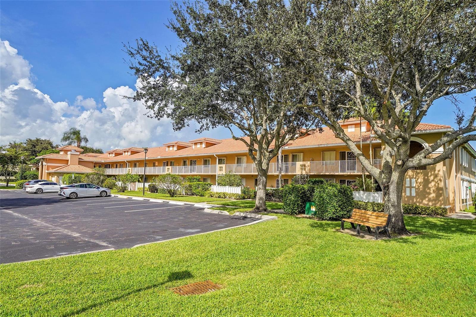 A multi-story apartment building with a parking lot, green lawn, and large trees — 5876 Regal Glen Drive # 201, Boynton Beach FL 33437, BOYNTON BEACH, FL