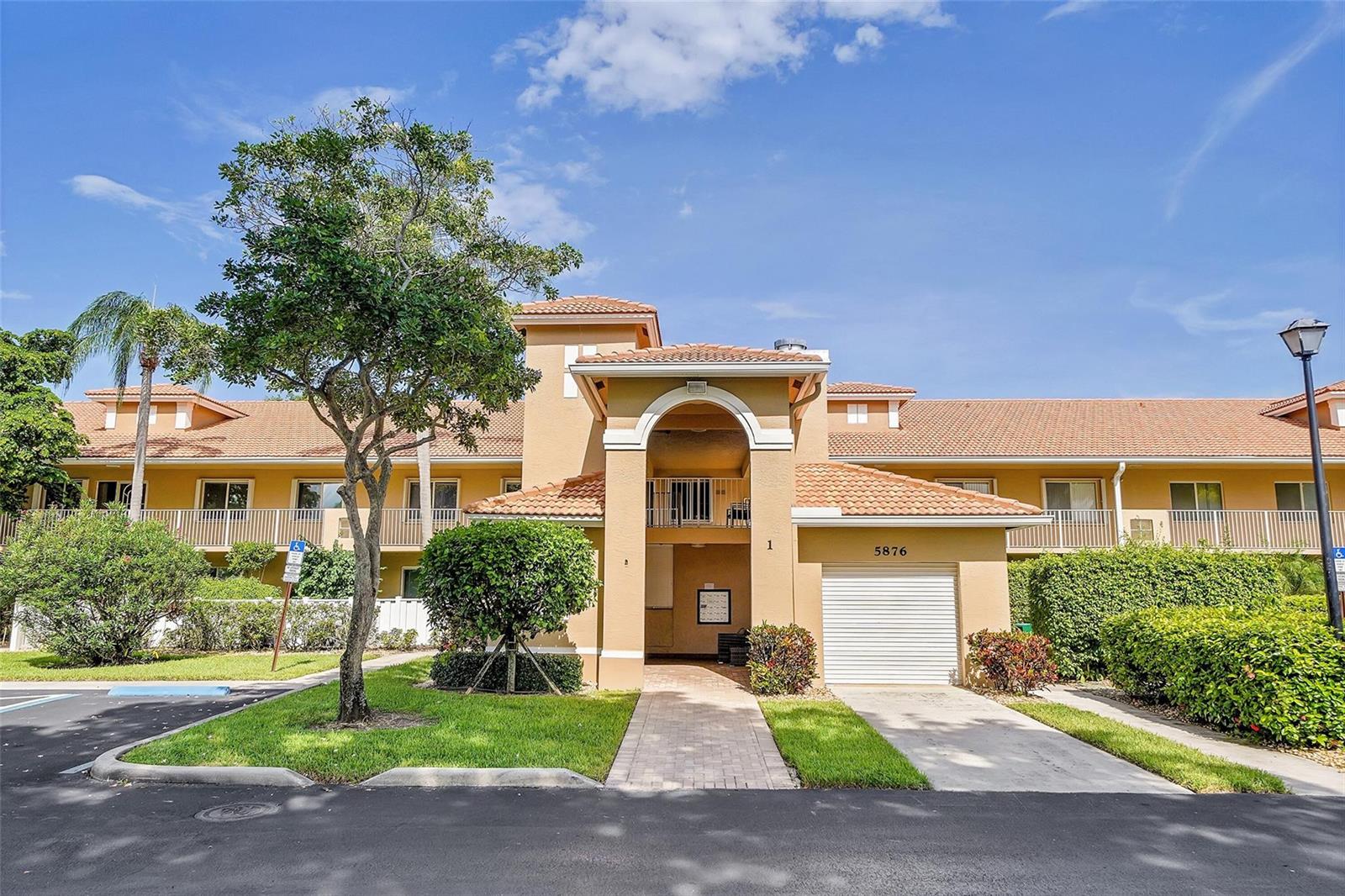 A two-story tan stucco building with a tile roof, a garage, and a paved walkway — 5876 Regal Glen Drive # 201, Boynton Beach FL 33437, BOYNTON BEACH, FL