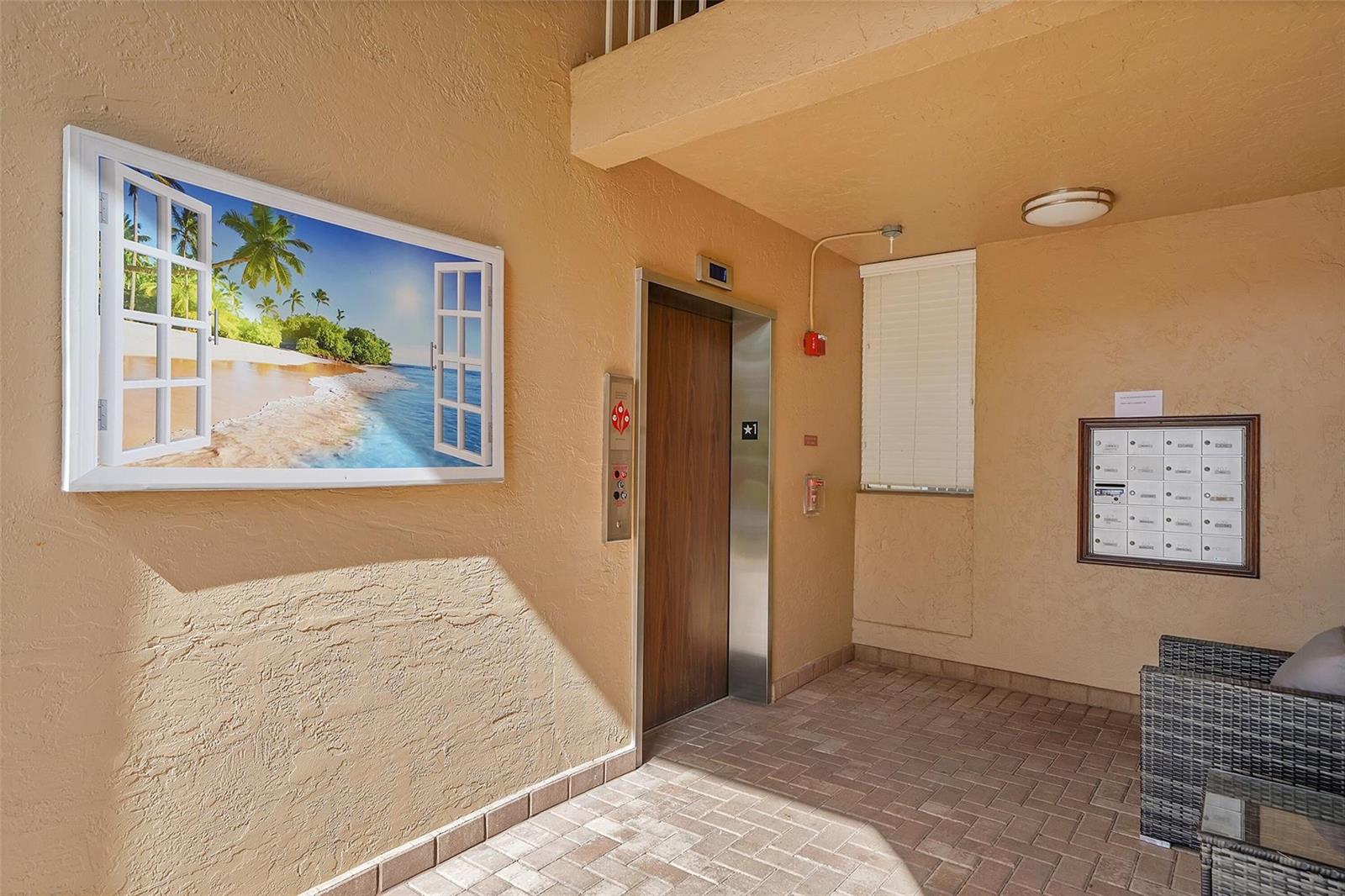 An elevator lobby features a beach-themed wall art, a mailbox unit, and brick flooring — 5876 Regal Glen Drive # 201, Boynton Beach FL 33437, BOYNTON BEACH, FL