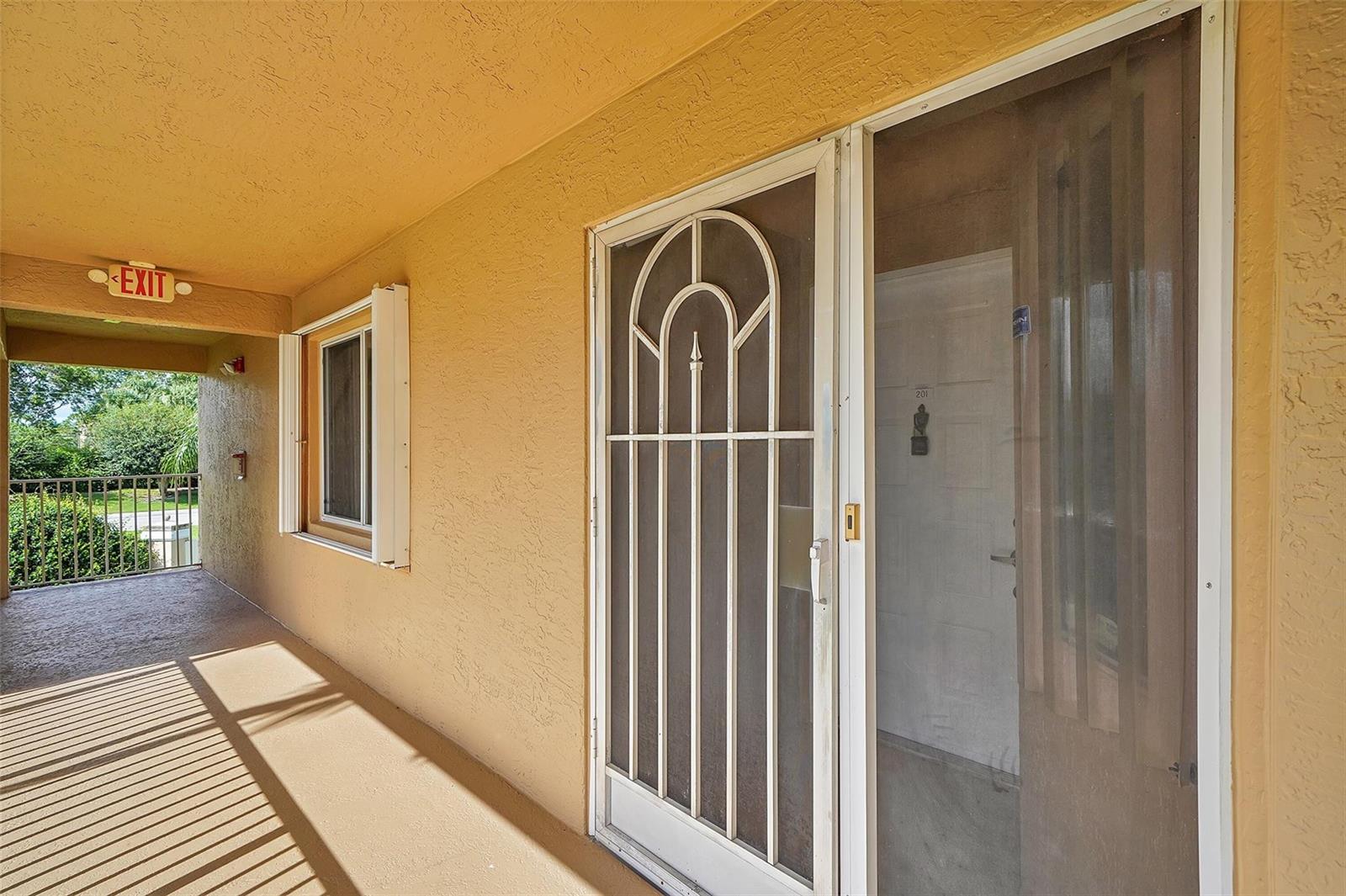 An exterior view of an apartment balcony featuring a screen door and a window — 5876 Regal Glen Drive # 201, Boynton Beach FL 33437, BOYNTON BEACH, FL
