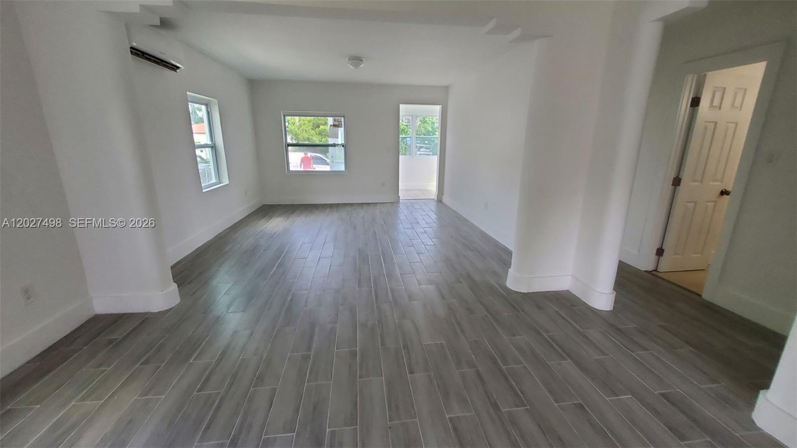 An empty room features white walls, gray wood-look tile flooring, and a white door — 560 NW 53rd St, Miami FL 33127, MIAMI, FL