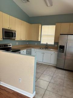 A kitchen features light-colored cabinets, stainless steel appliances, a tile floor, and a partial wall — 5642 Sunberry Circle, Fort Pierce FL 34951, FORT PIERCE, FL