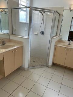 A bathroom features a glass-enclosed corner shower between two light wood vanities with tiled floors — 5642 Sunberry Circle, Fort Pierce FL 34951, FORT PIERCE, FL