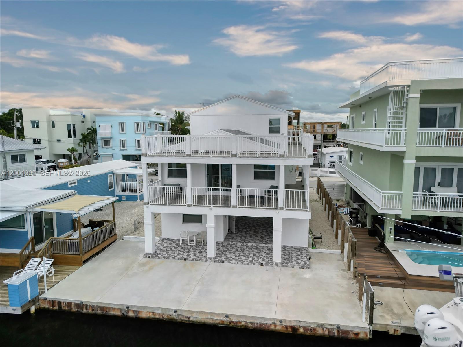 A three-story white house with balconies sits on a concrete waterfront lot with a dock — 20 Eagle Dr, Key Largo FL 33037, KEY LARGO, FL